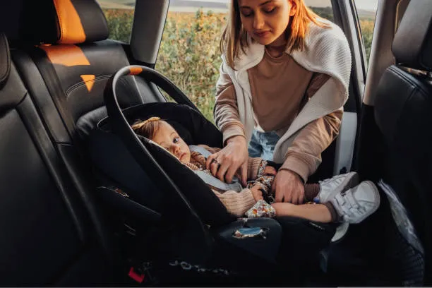 A parent buckling a baby into a car seat
